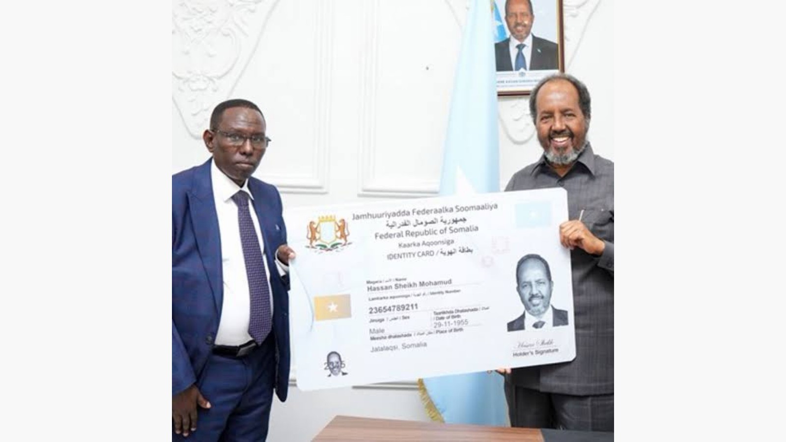 President Hassan Sheikh Mohamud holding an oversized Somali National Identity Card beside a NIRA official.