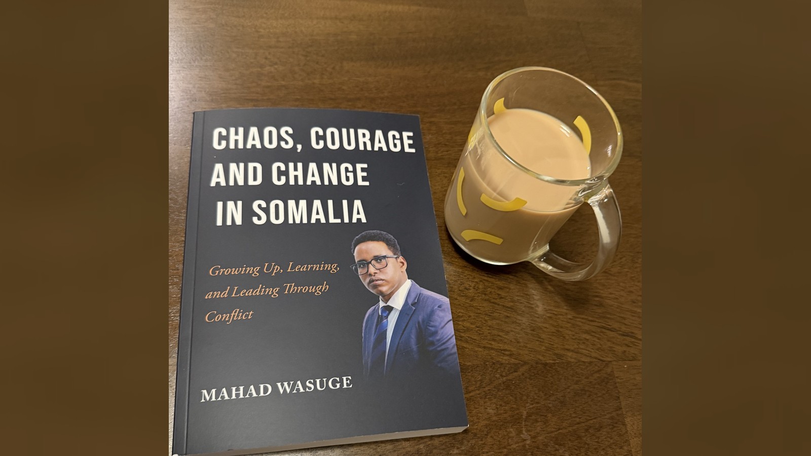 Mahad Wasuge’s memoir Chaos, Courage and Change in Somalia on a table beside a glass of shaah.
